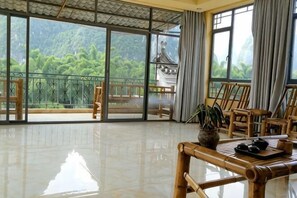 A spacious room with large windows, a polished floor, and traditional wooden furniture. - Laozheng Homestay (Yangshuo)