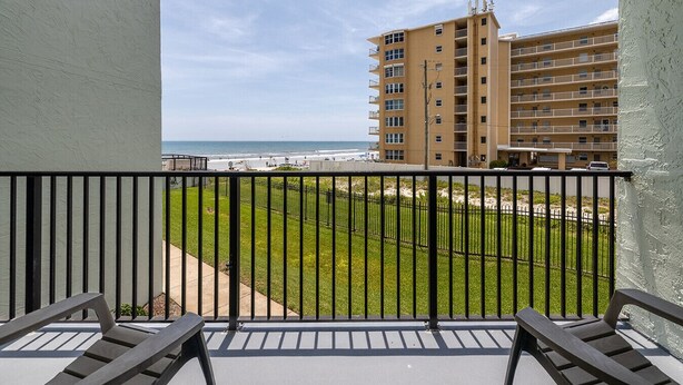 A balcony with a view of a beach and a multi-story building.