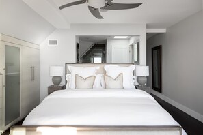 Un dormitorio moderno con una cama grande, un ventilador de techo, un armario y un espejo.