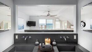 A modern bathroom with two sinks, a ceiling fan, and a view of the ocean. - Luxury Oceanfront, Two-Level Condo with Stunning View, Decks, Fast WiFi & Fireplace! (San Diego)