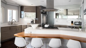 A modern kitchen with a central island, white cabinetry, and stainless steel appliances. - Luxury Oceanfront, Two-Level Condo with Stunning View, Decks, Fast WiFi & Fireplace! (San Diego)