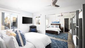 A hotel room with a bed, a chair, a TV, a ceiling fan, and a large mirror. - Luxury Oceanfront, Two-Level Condo with Stunning View, Decks, Fast WiFi & Fireplace! (San Diego)