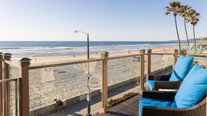 A beach view from a balcony with wicker furniture and a clear sky. - Luxury Oceanfront, Two-Level Condo with Stunning View, Decks, Fast WiFi & Fireplace! (San Diego)