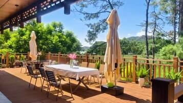 An outdoor patio with tables and chairs, a wooden fence, and potted plants.