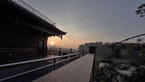 Un bâtiment traditionnel doté d’un balcon donnant sur un paysage pittoresque au coucher du soleil.