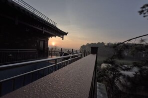 A traditional building with a balcony overlooking a scenic landscape during sunset. - Yunshui Hulin Inn Puzhehei (Qiubei)