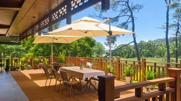 Un patio al aire libre con una mesa y sillas, rodeado por una valla de madera, con vistas a un paisaje exuberante.