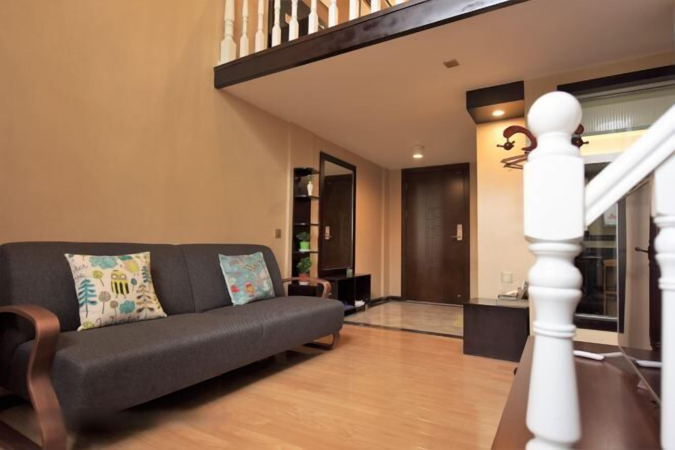 Un salon avec un canapé gris foncé, une table basse en bois et un escalier doté de balustrades blanches.