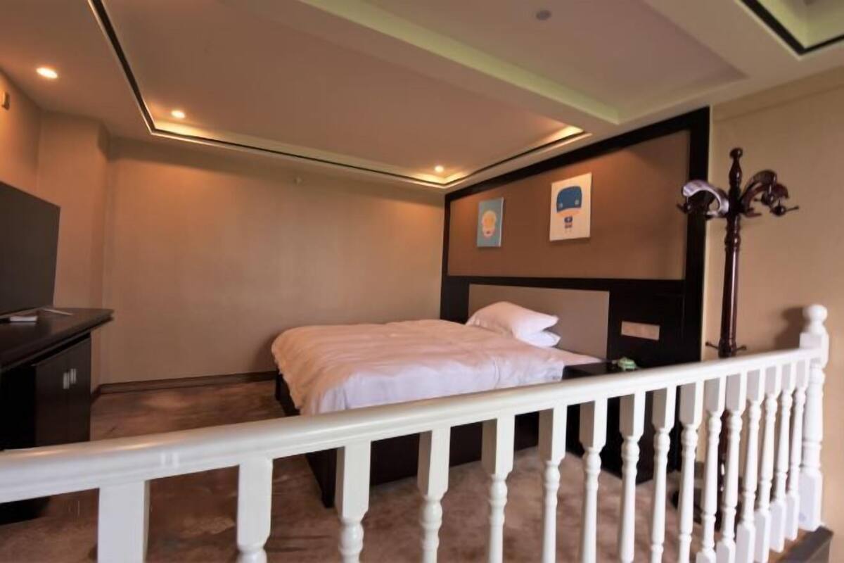 A bedroom with a bed, a desk, and a nightstand.