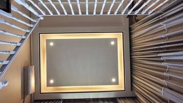 A modern staircase with a light fixture at the top and a textured wall on the right.