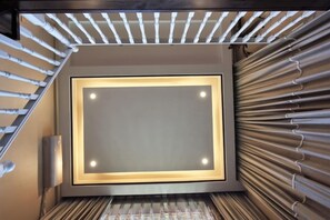 Una escalera de diseño moderno, un cuadro enmarcado en la pared y un revestimiento con estampado a la derecha.