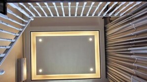 A modern staircase with a light fixture at the top and a textured wall on the right.