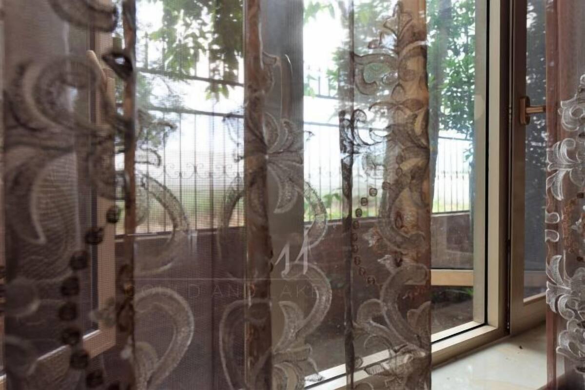A sliding glass door with intricate patterns, leading to a view of a fence and greenery outside.