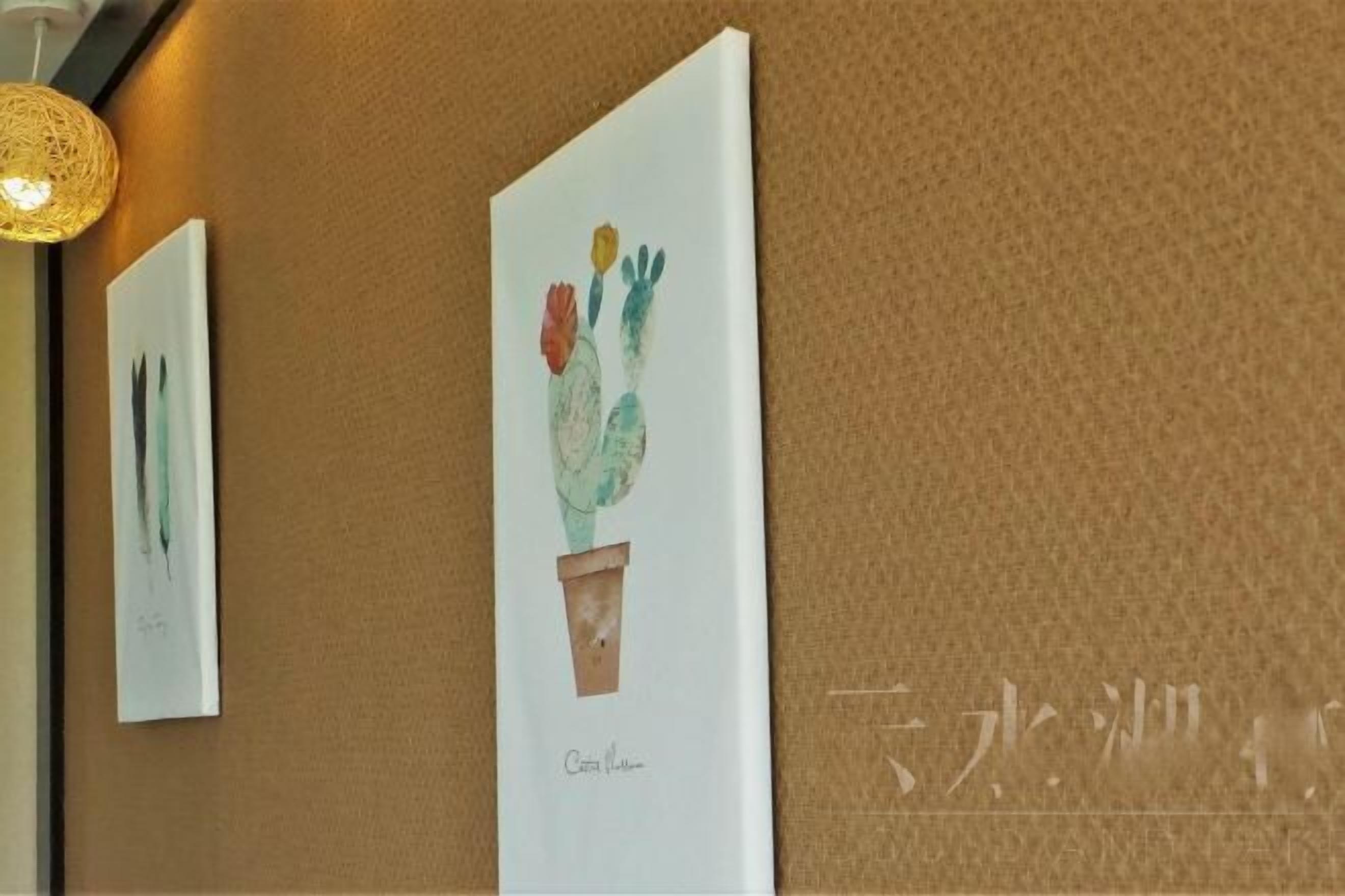 Una obra de arte en una pared con textura, una lámpara colgante y una vista parcial de una habitación.