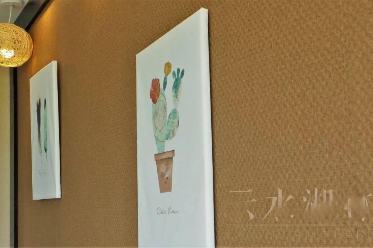 Artwork on a textured wall, a hanging light fixture, and a partial view of a room.