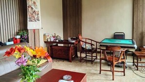 Une pièce avec une table de billard, des chaises en bois, un canapé et un vase de fleurs.