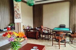A room with a pool table, wooden chairs, a sofa, and a vase of flowers. - Yunshui Hulin Inn Puzhehei (Qiubei)