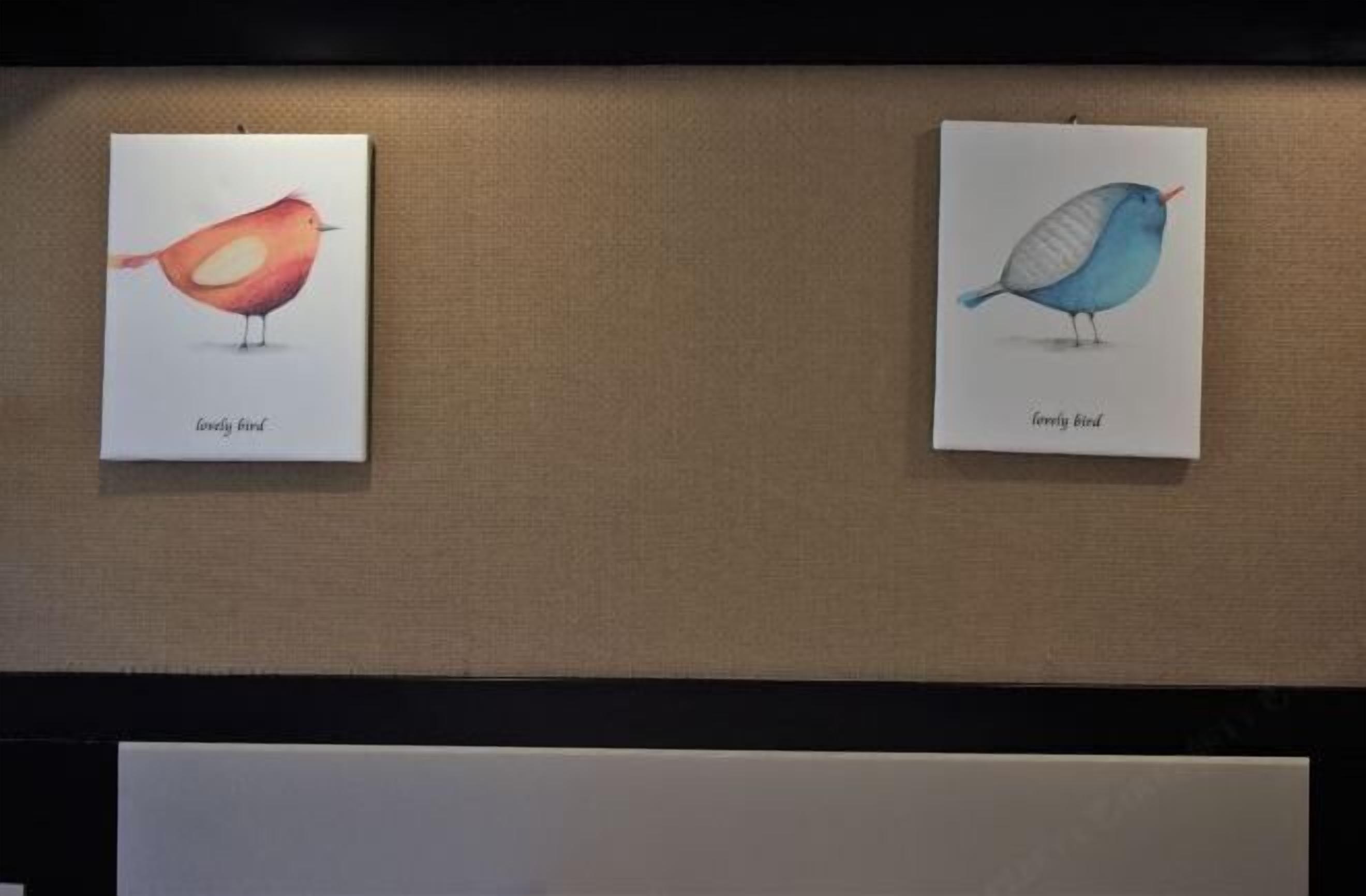 Dos ilustraciones enmarcadas de pájaros en una pared.