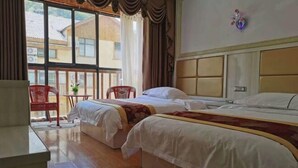 A hotel room with two beds, a small table, chairs, and a large window with a view of buildings. - Shennongjia Meets Miss Meow Hotel (Shennongjia)