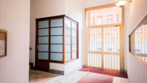 A hallway with a wooden cabinet, a red carpet, and a door with a metal gate. - [ISOLA] Loft Taramelli (Milano)