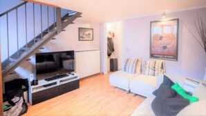 A living room with a sofa, a TV, and a staircase. - [ISOLA] Loft Taramelli (Milano)