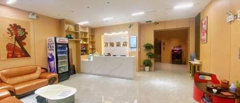 Un hall de hotel con asientos de cuero, un mostrador de recepción y una máquina expendedora.