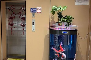 An elevator with a decorative red pattern, a no-smoking sign, and a water feature with fish. - Wanlonghote (Cenxi)