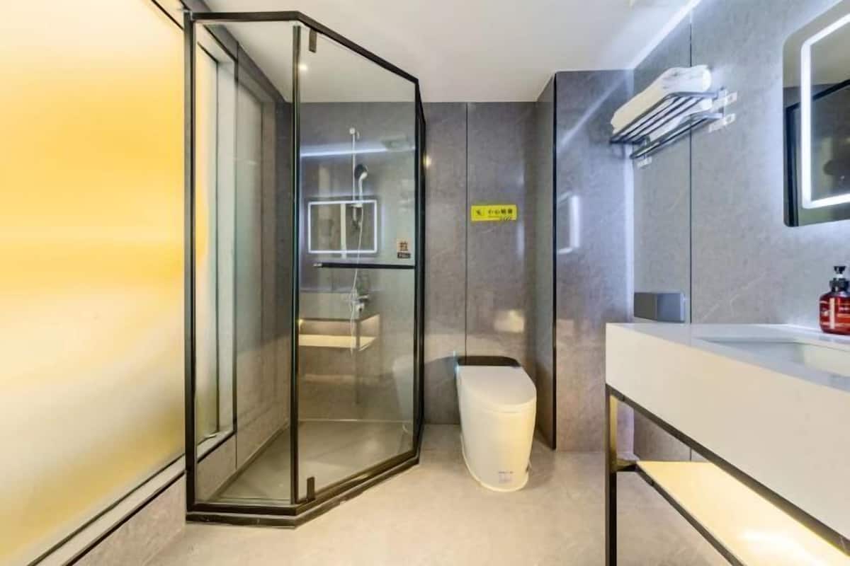 A modern bathroom with a glass-enclosed shower, a white toilet, and a sink with a mirror.