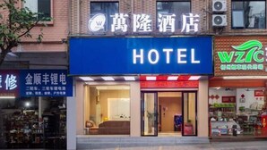 A hotel with a prominent 'HOTEL' sign, a visible entrance, and a storefront with a green logo. - Wanlonghote (Cenxi)