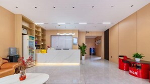A reception area with a white reception desk, a red counter, a sofa, and a coffee table with a vase of flowers. - Wanlonghote (Cenxi)