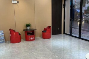 A hotel lobby with a seating area featuring red chairs and a small table with a plant. - Wanlonghote (Cenxi)