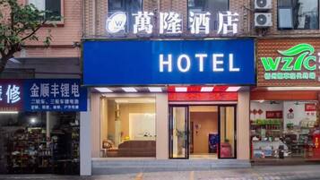 Un hotel con un letrero azul llamativo, una entrada visible y un escaparate con diversos artículos expuestos.