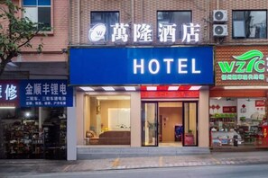 A hotel with a prominent blue sign, a visible entrance, and a storefront with various items displayed outside. - Wanlonghote (Cenxi)