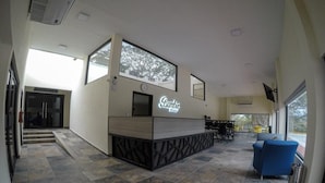 Un área de recepción con diseño moderno, que incluye un mostrador de recepción, zona de estar y ventanas amplias que ofrecen luz natural.