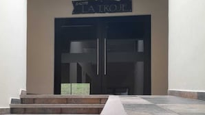 Entrada de un edificio con un letrero que dice "LA TROIE" sobre una puerta doble.