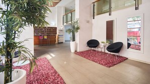 A modern interior with a reception desk, seating area, and a large potted plant. - "Live life to the fullest in the heart of Santiago"! (Santiago)