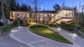 Un hotel moderno con una estructura de varios pisos, un espacio acristalado y un jardín ajardinado.
