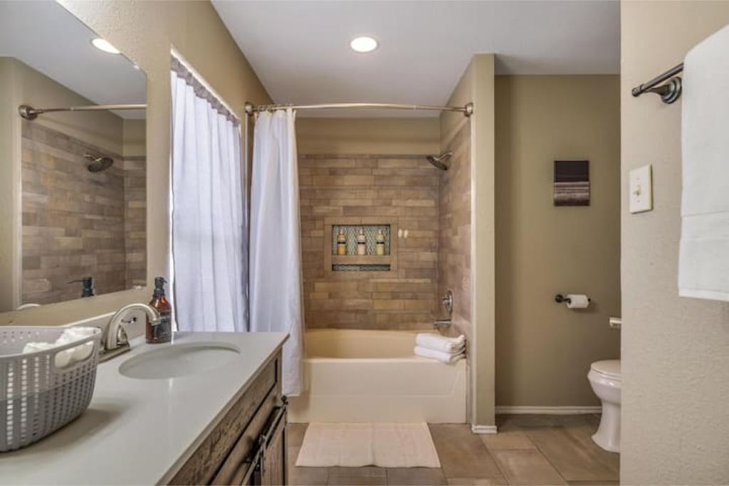 A bathroom with a double sink, a bathtub, and a toilet.