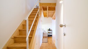 Eine Holztreppe führt zu einem Küchenbereich mit einer weißen Wand und einer Tür mit silberner Griff.