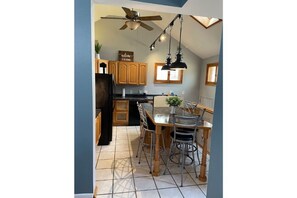 Enjoy meals and relaxation in this cozy kitchen with a central island dining space, featuring a bathtub, wooden cabinets, and a ceiling fan.