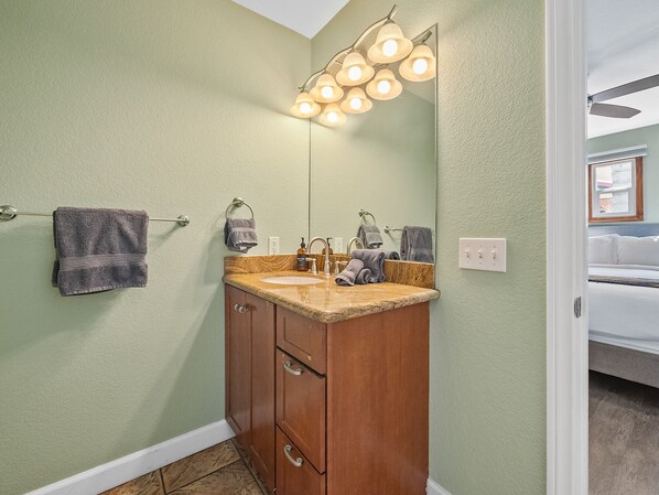 A bathroom with a vanity, mirror, towel rack, and a ceiling fan.