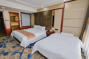 Habitación de hotel con dos camas, un espejo grande, cabecero de madera y alfombra con diseño azul y beige.