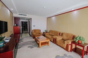 A modern living room with a sofa, armchairs, a coffee table, and a TV on a wooden desk. - Boyin Hotel (Jiang County)
