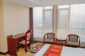 A hotel room with a bed, a desk, two chairs, and large windows with sheer curtains. - Boyin Hotel (Jiang County)
