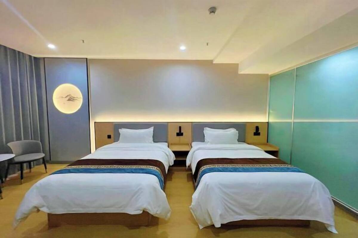 A hotel room with two beds, a desk, and a chair.