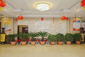 A lobby with a marble wall, potted plants, and red lanterns. - Boyin Hotel (Jiang County)