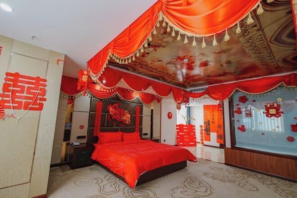 A room with a red bedspread, a large bed, and a ceiling with red and gold decorations. - Boyin Hotel (Jiang County)