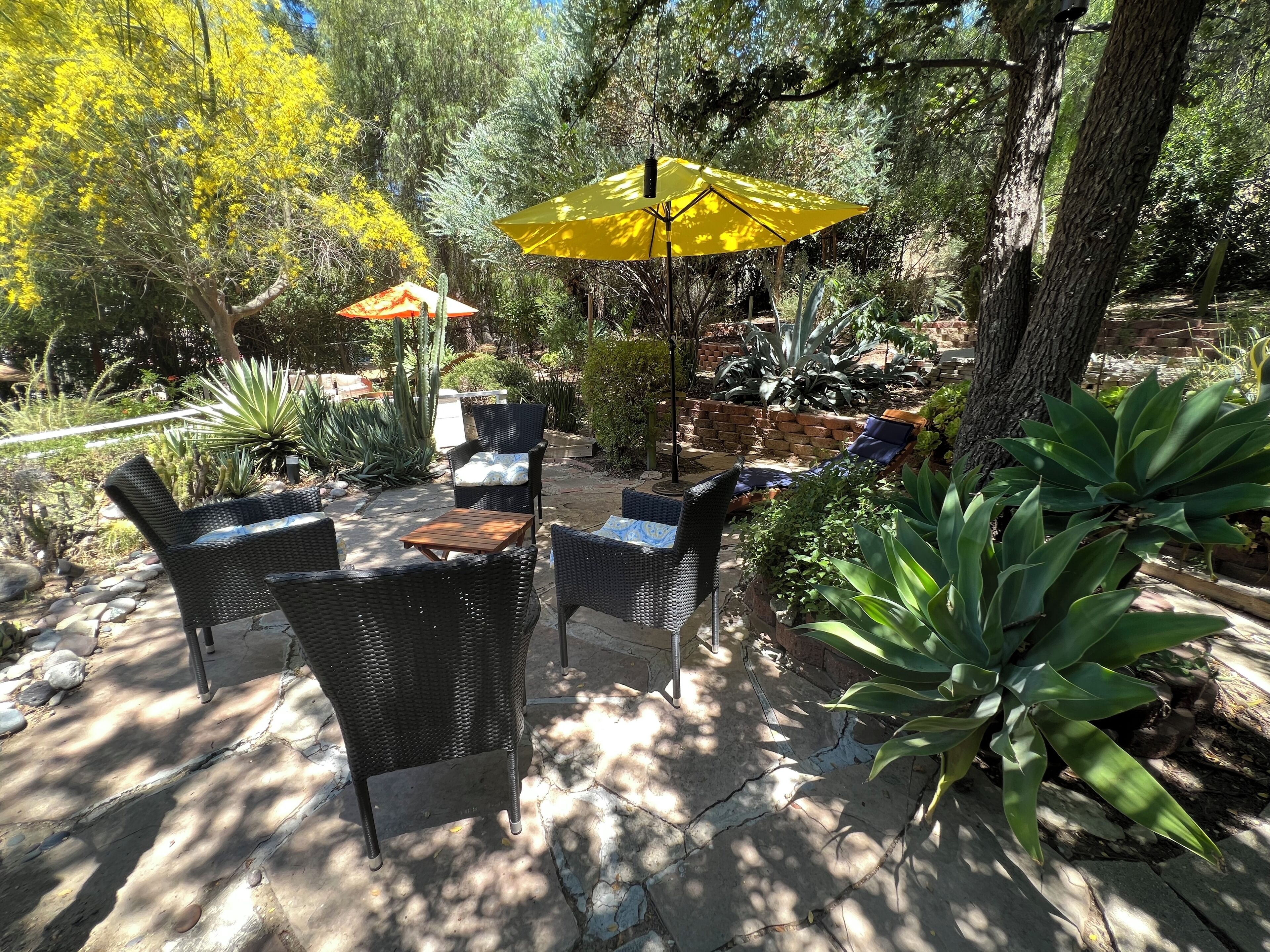 Un patio al aire libre con mobiliario de mimbre y un paraguas amarillo.