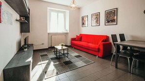 Una sala de estar moderna con un sofá rojo, una mesa de comedor y un tapete blanco y negro.