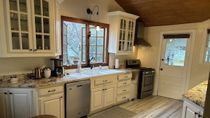 Une cuisine avec des meubles blancs, un lave-vaisselle, une cuisinière et un évier.